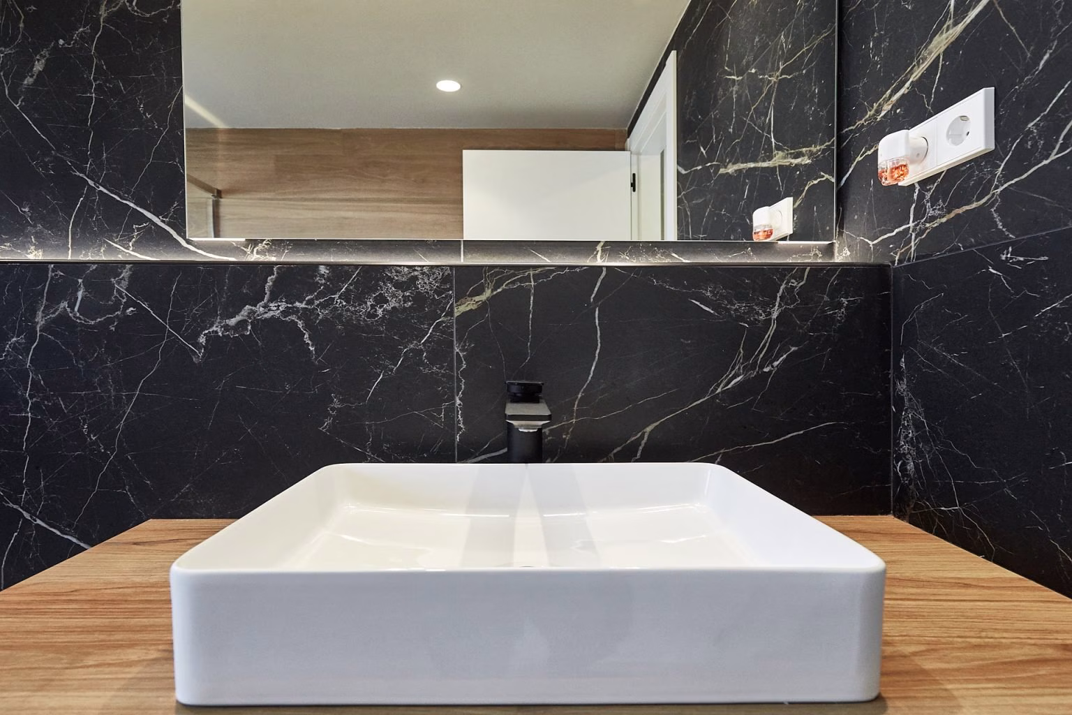 Lavabo blanco rectangular sobre encimera de tono madera