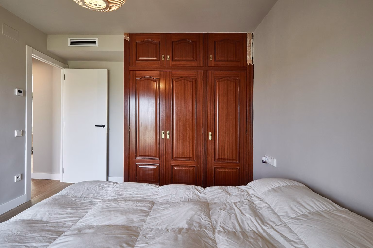 Dormitorio con armario oscuro de puertas con molduras