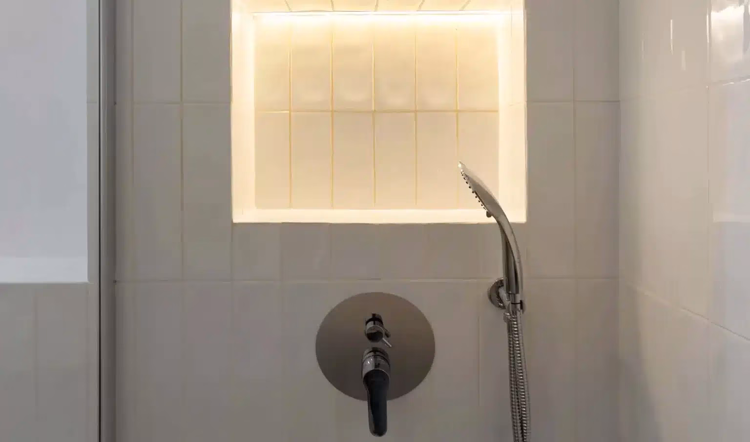 Nicho iluminado sobre la grifería de la ducha