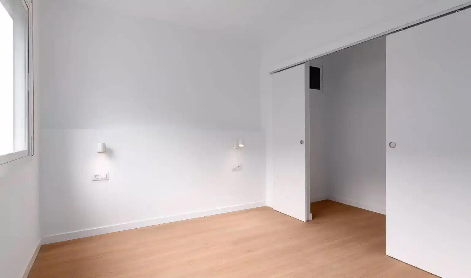 Dormitorio blanco con puerta corredera abierta