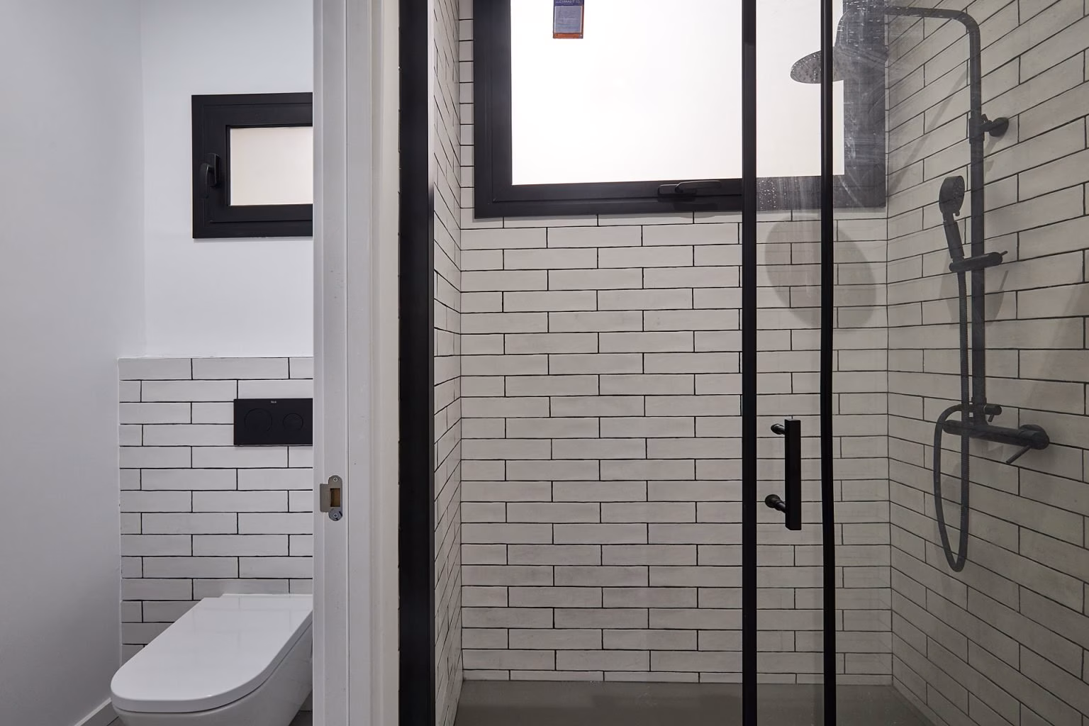 Ducha con azulejos blancos y perfiles negros