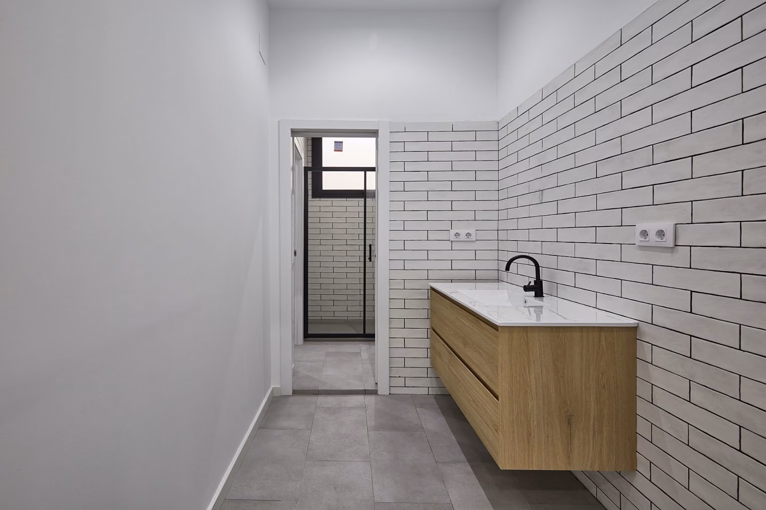 Lavabo suspendido de tono madera bajo pared alicatada