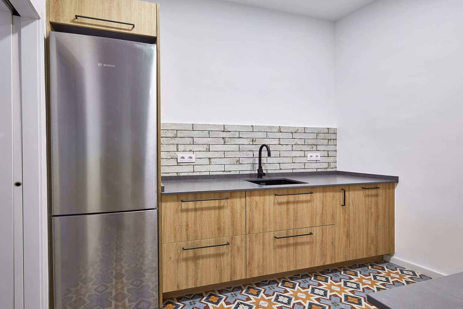 Cocina de tono madera con encimera oscura y suelo geométrico