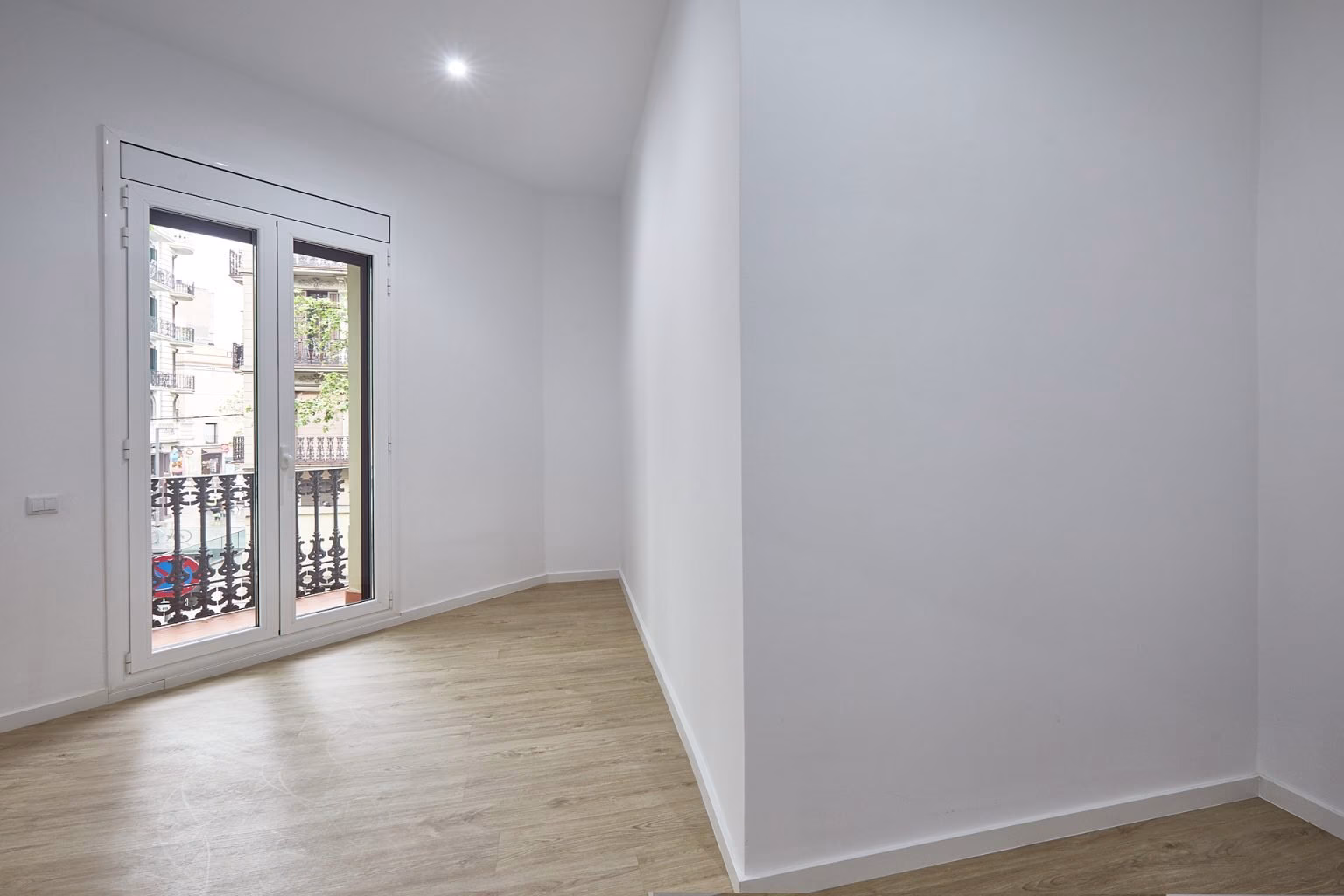 Habitación estrecha con puerta acristalada a balcón