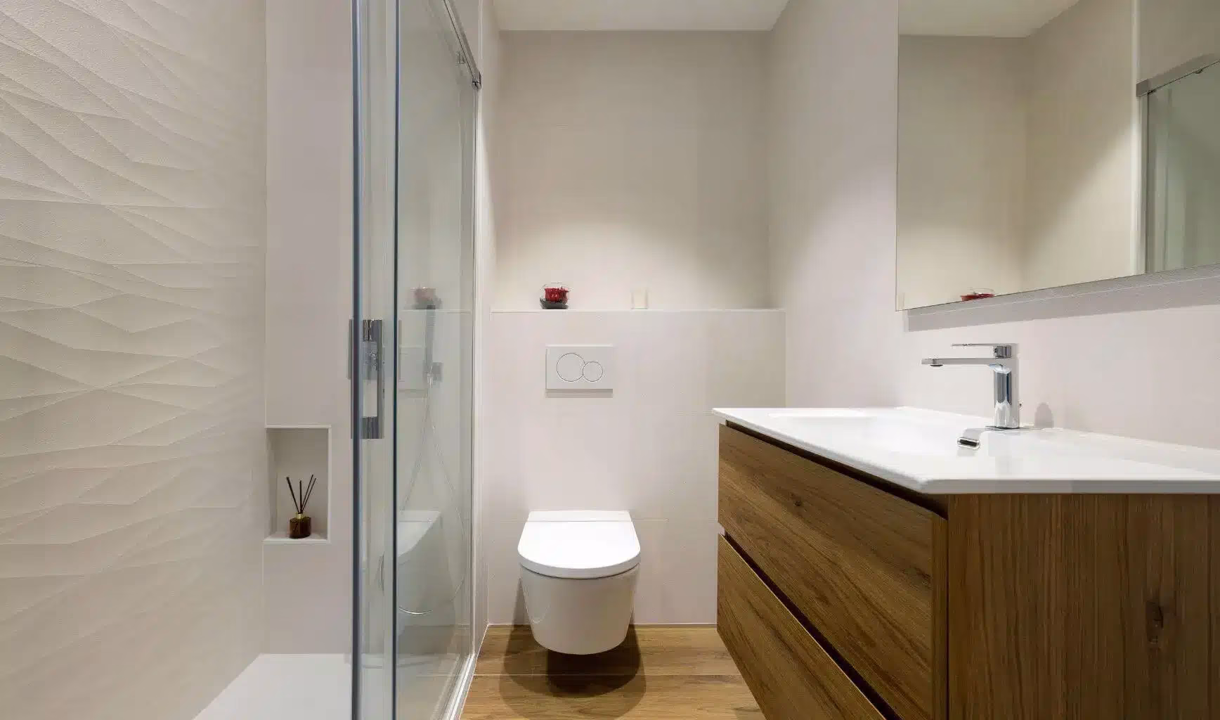 Baño con ducha, pared de relieve y mueble de tono madera