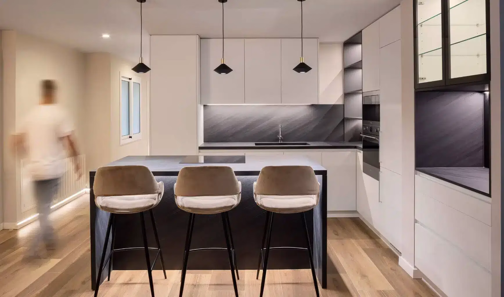 Cocina blanca con barra oscura y tres taburetes