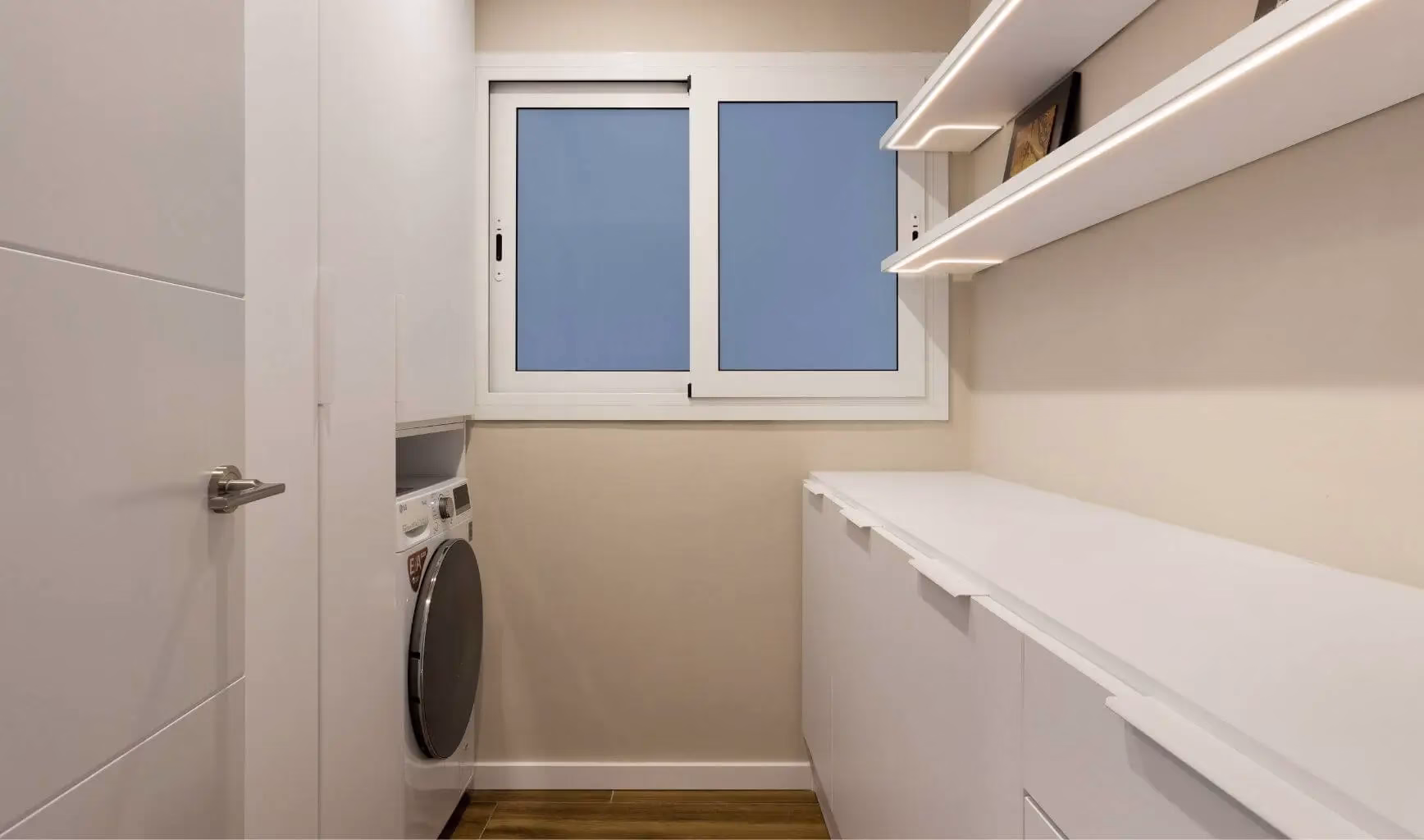 Lavadero blanco con lavadora junto a ventana