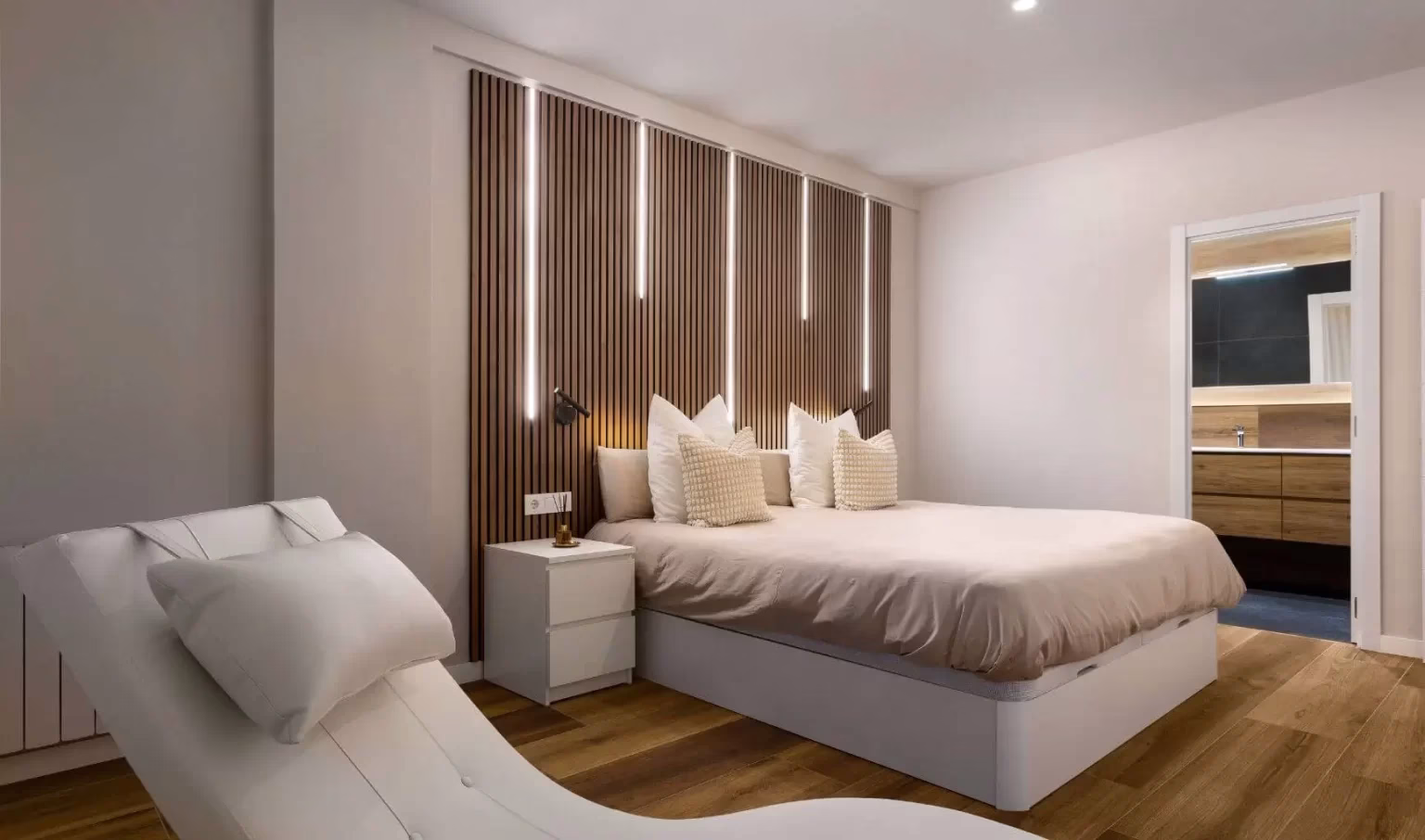 Dormitorio con cabecero de listones y butaca clara