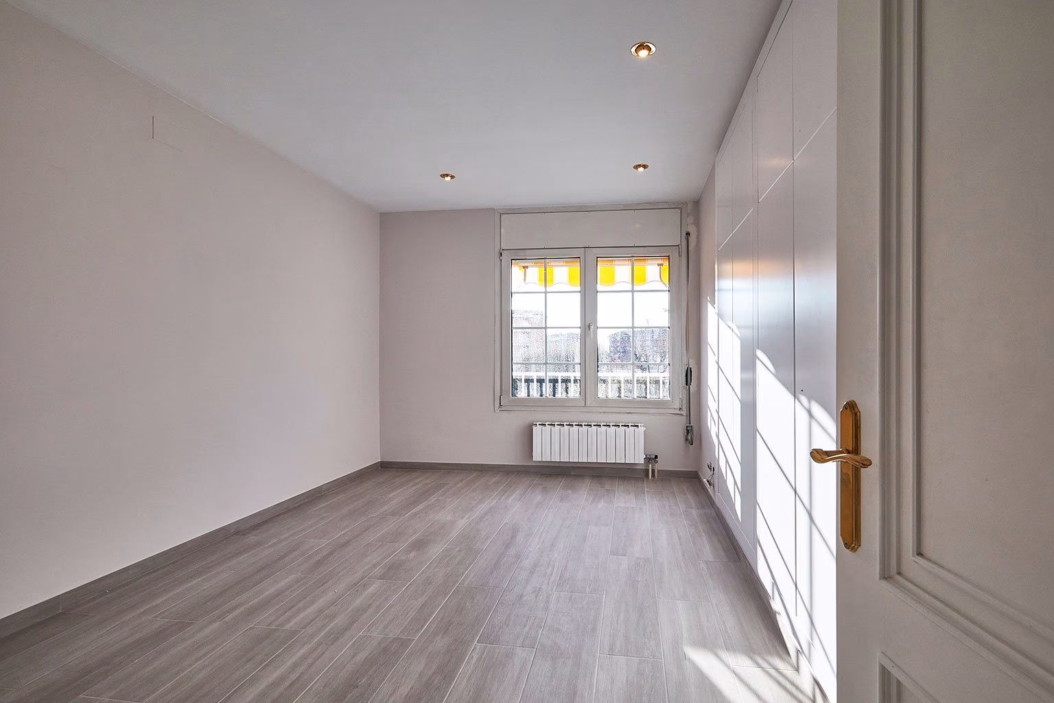 Dormitorio con armario blanco y ventana al fondo