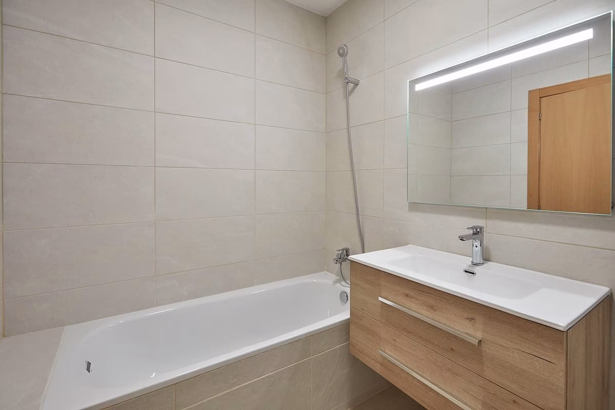 Bañera blanca junto a lavabo de acabado madera