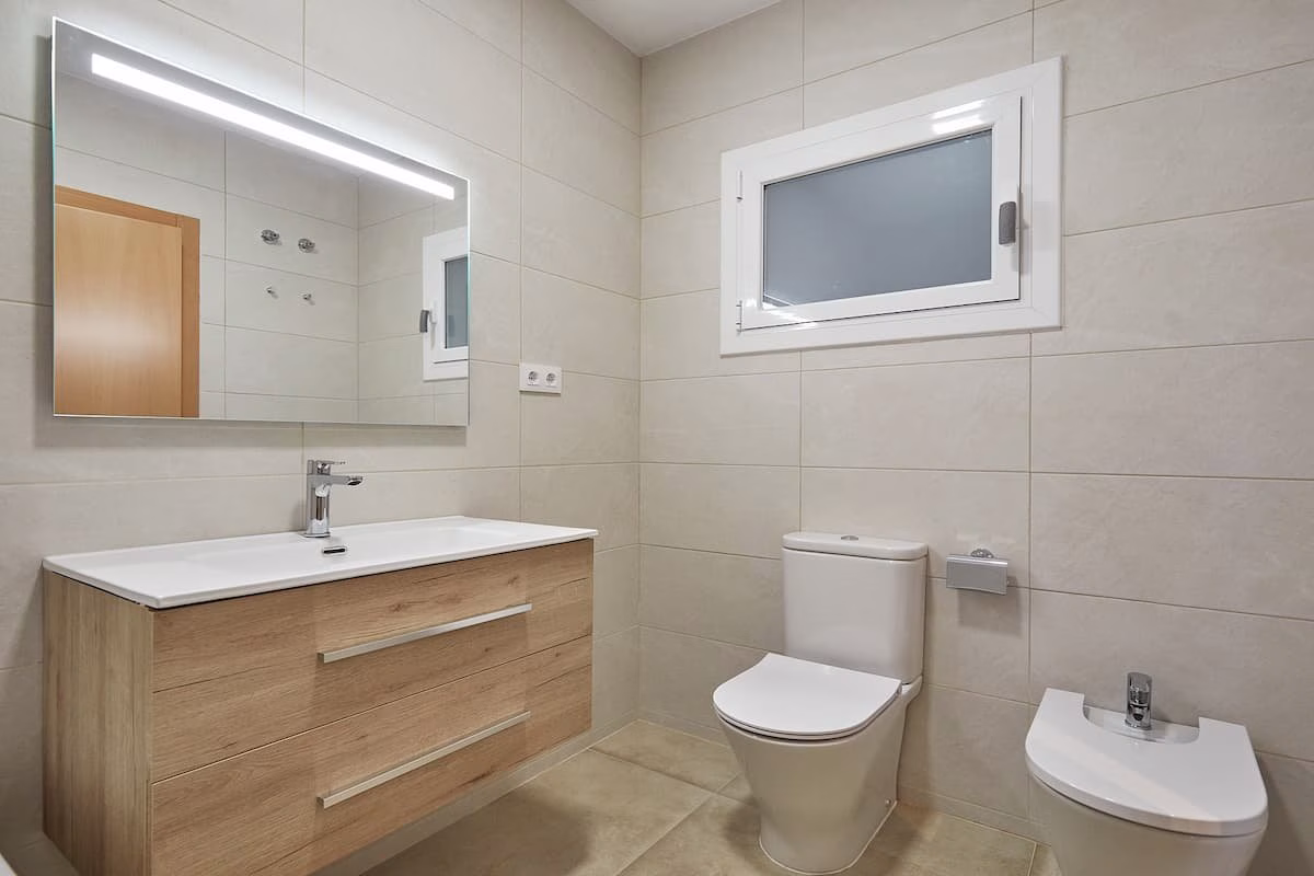 Baño beige con lavabo suspendido, inodoro y bidé