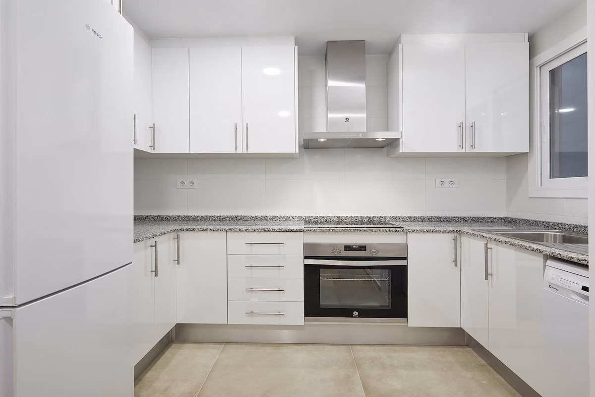 Cocina blanca en U con horno central y encimera moteada