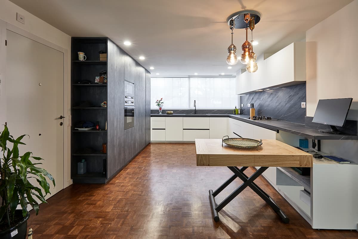 Cocina en L con mesa de apoyo y columnas oscuras
