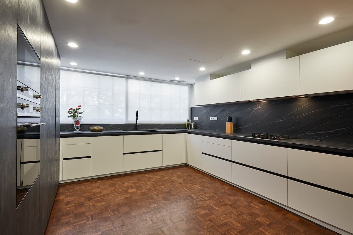 Cocina blanca con encimera oscura bajo la ventana