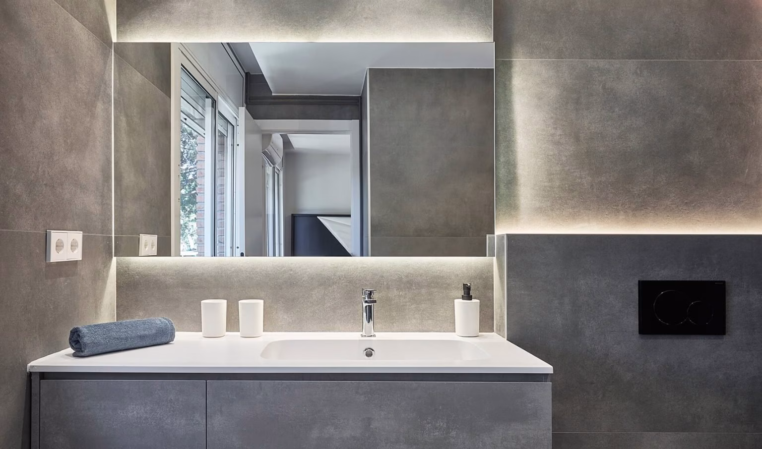 Lavabo gris bajo espejo de perímetro iluminado