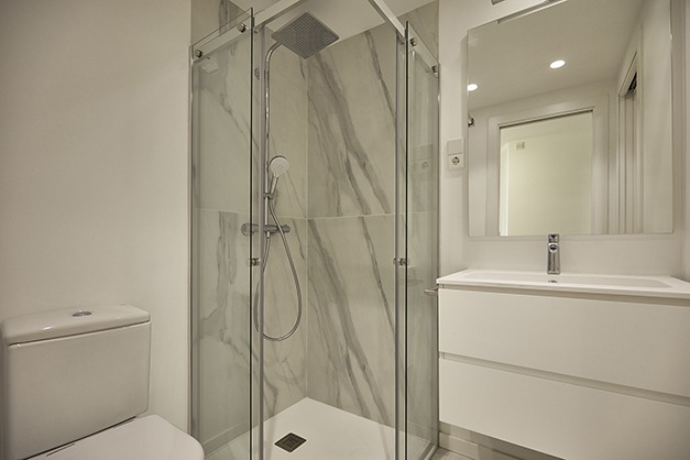 Baño con ducha transparente y pared veteada