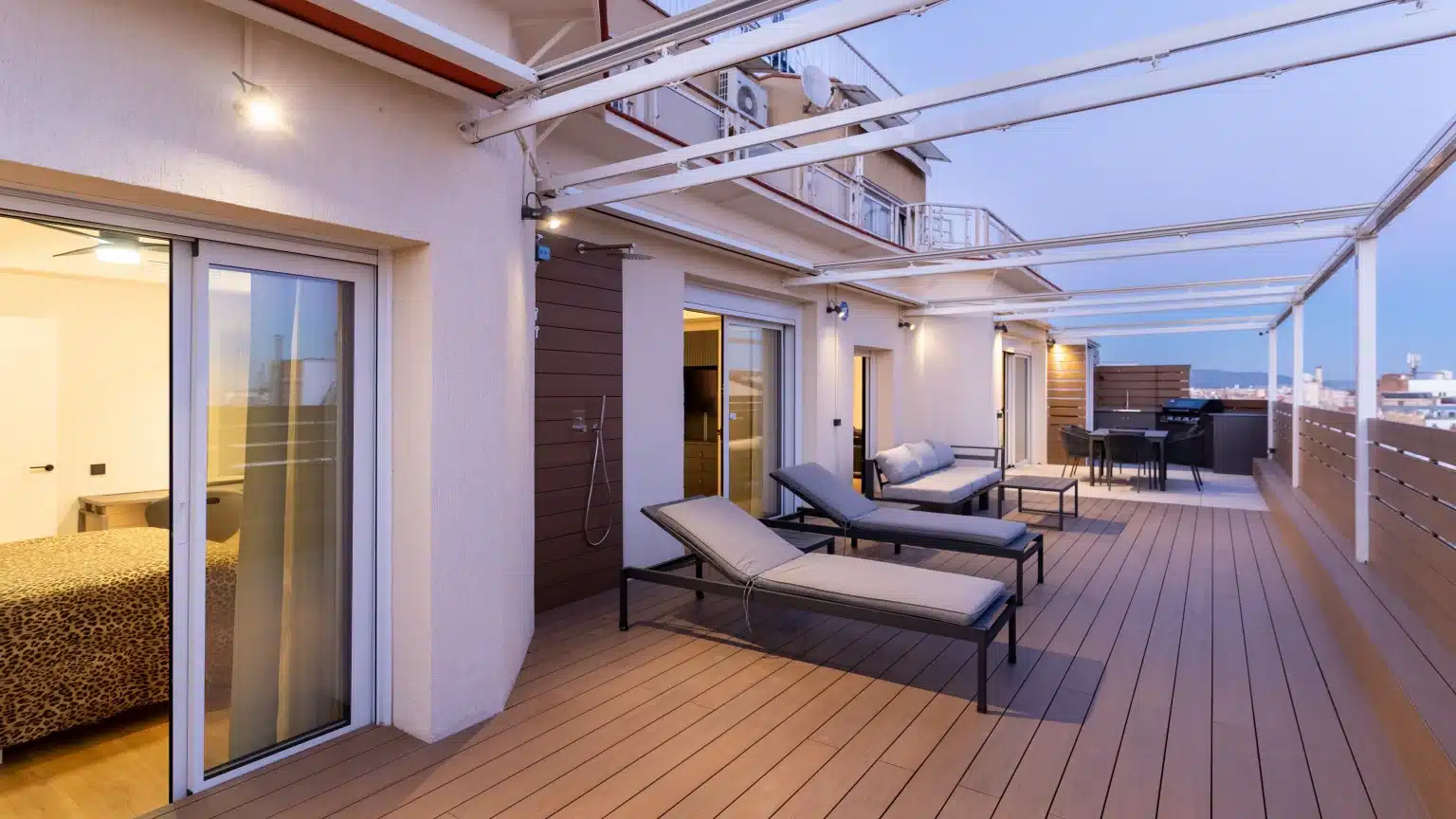 Terraza alargada con tumbonas bajo estructura superior