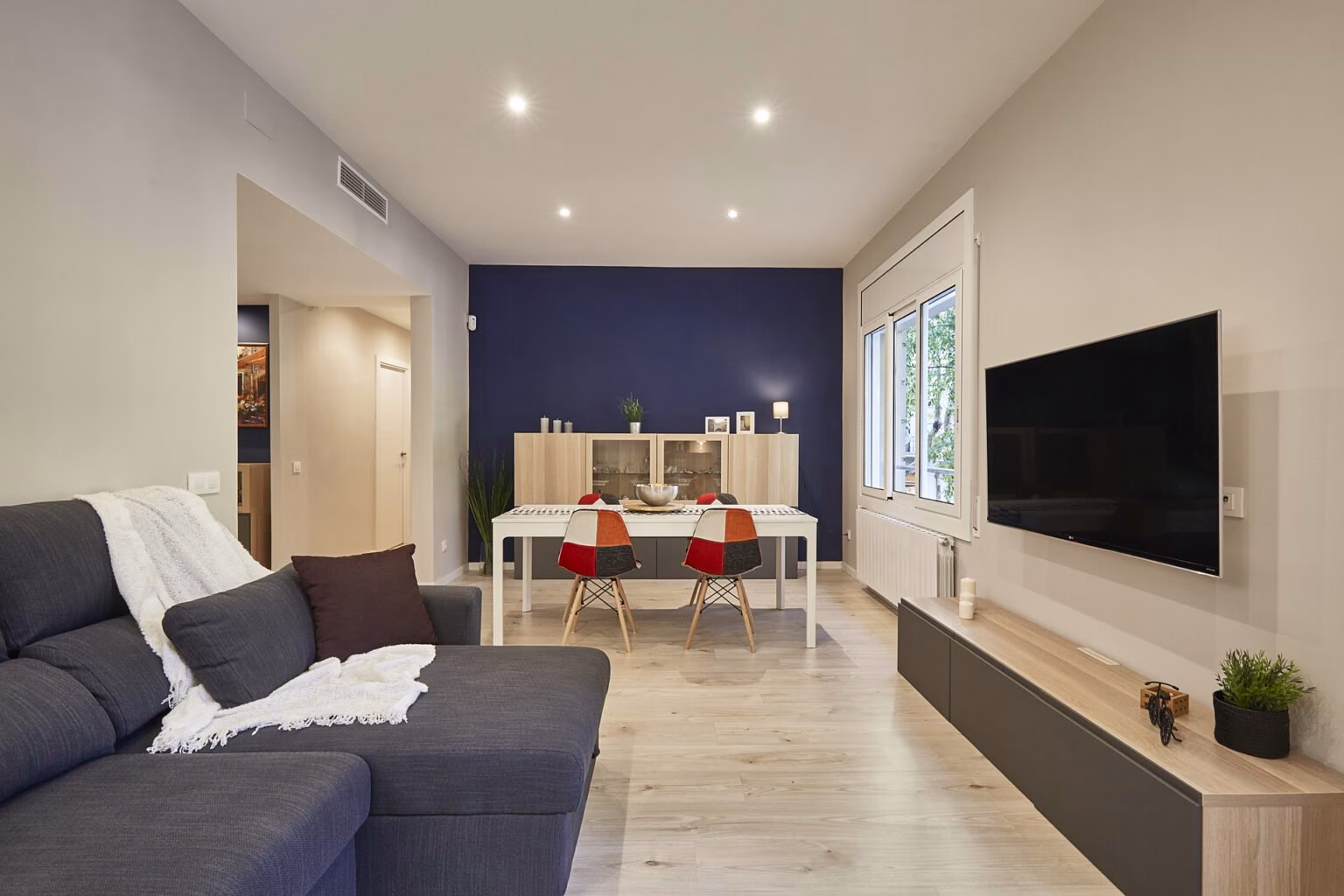 Salón alargado con comedor frente a pared azul