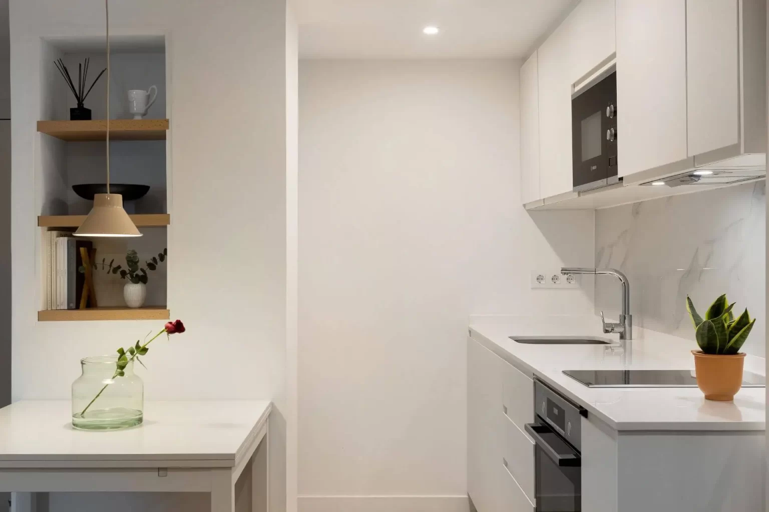 Mesa blanca junto a frente de cocina y estantes