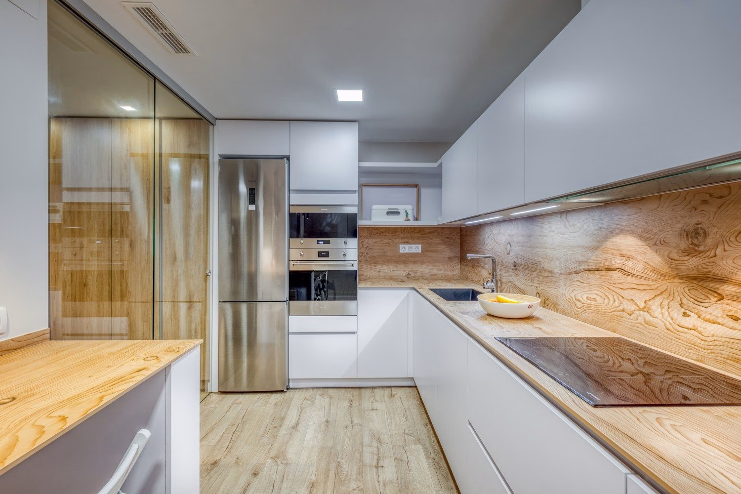 Frente blanco de cocina con revestimiento de vetas cálidas