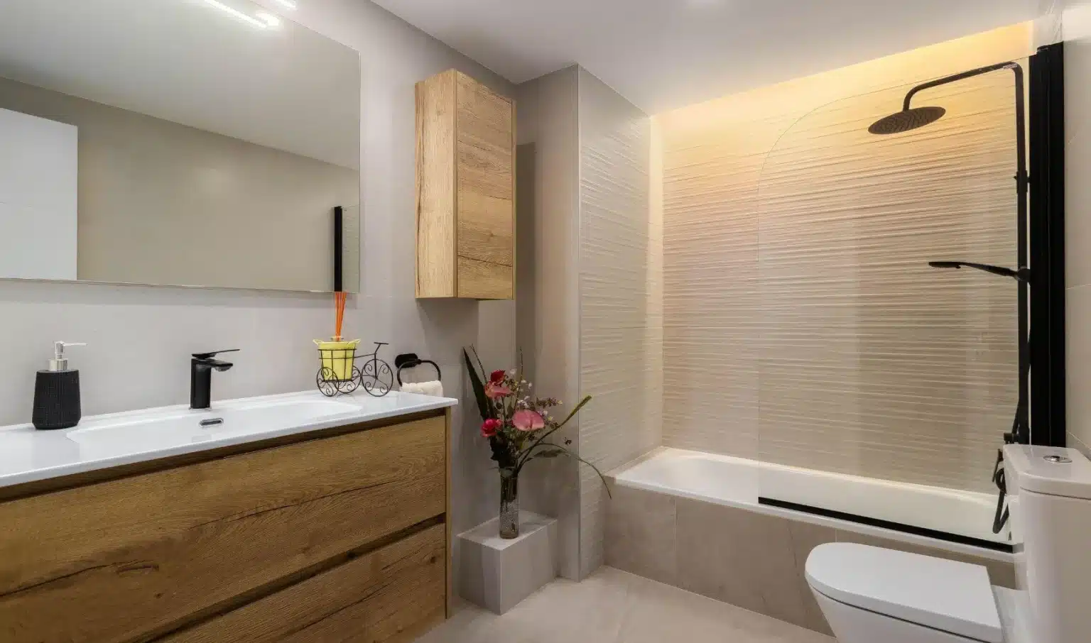 Baño con bañera, grifería negra y mueble de tono madera