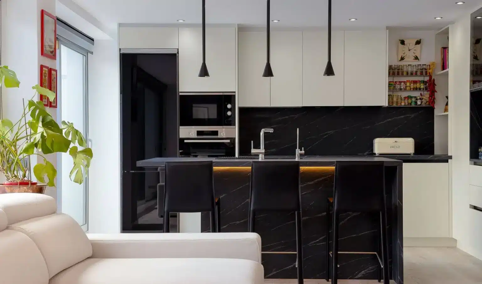 Cocina blanca con isla oscura y taburetes