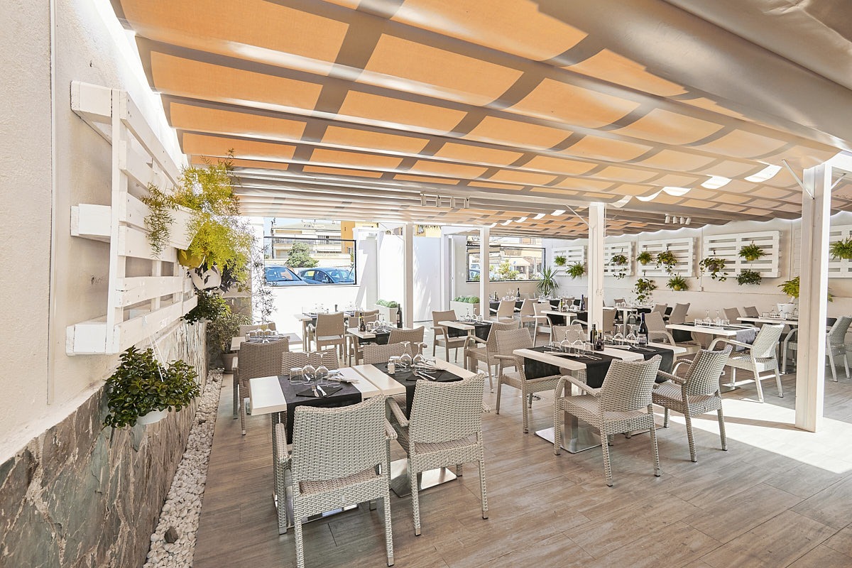 Terraza cubierta de restaurante con mesas, sillas y toldos cálidos